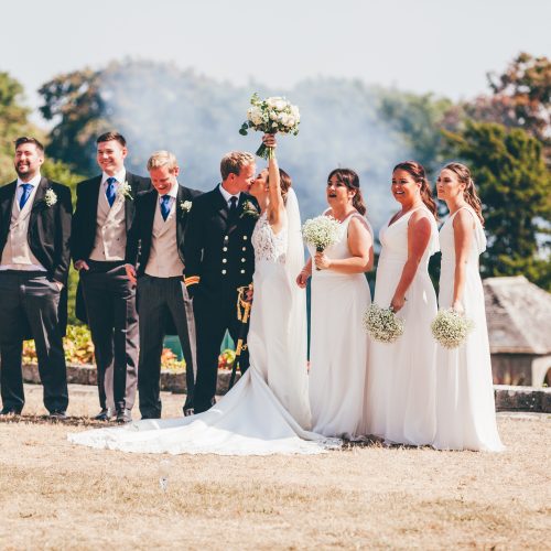 Wedding venue, South Wales Bride and groom kissing on top lawn with bridesmaids and groomsmen in a line