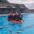 students on a lifesaving float device in an outdoor pool, training as part of summer camp