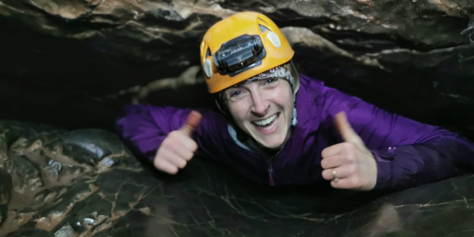 Lady in purple between rock in a cave