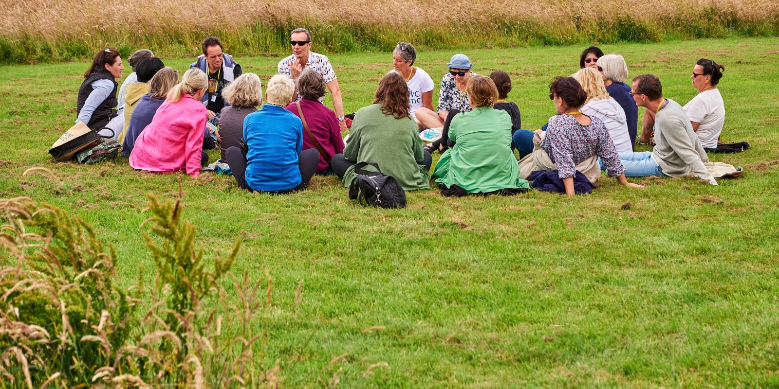 Group of individuals in a circle sat on the grass talking